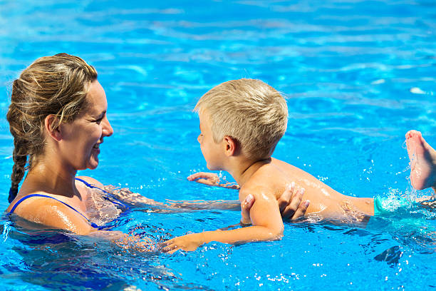 Mother teaching her son swimming in the pool.